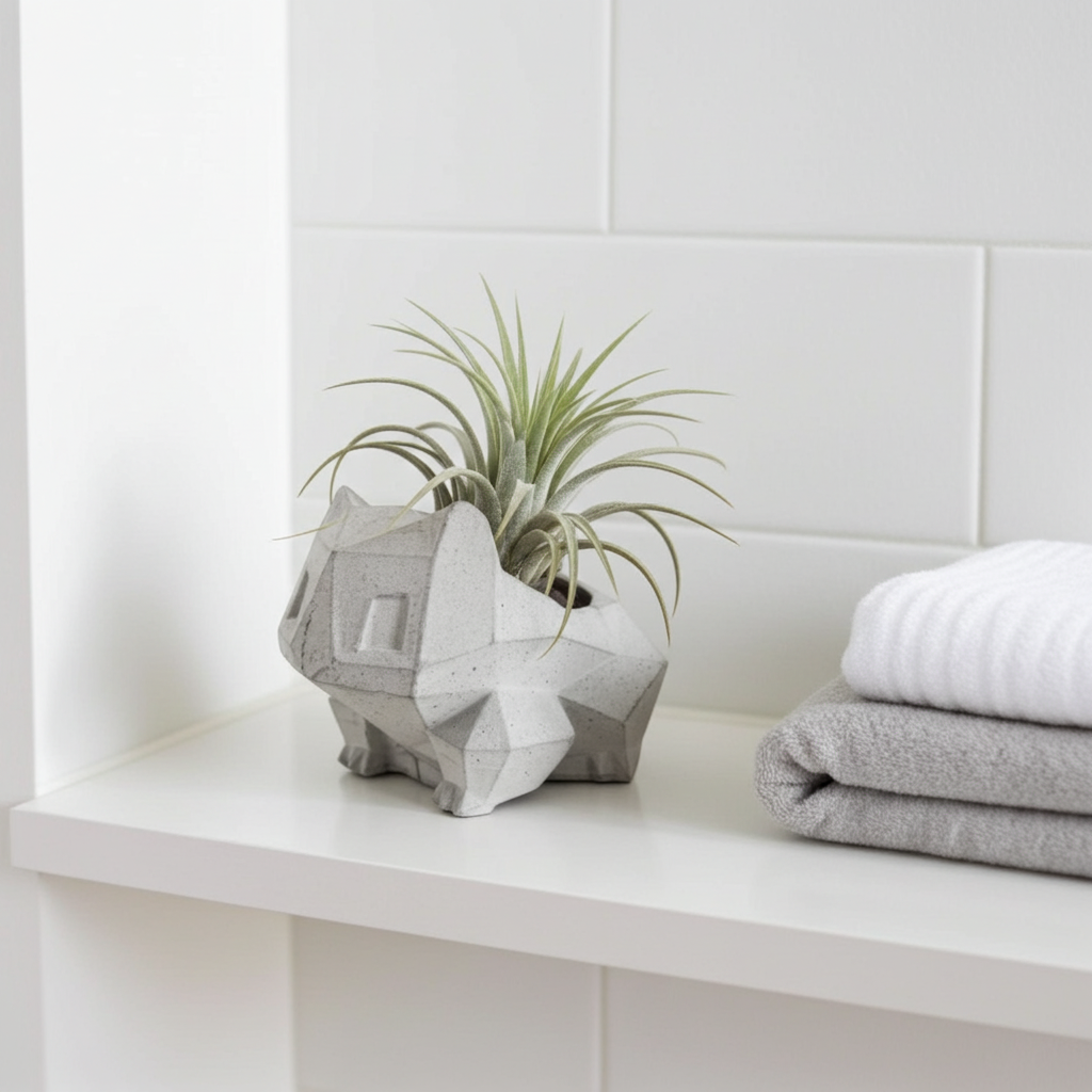 Geometric concrete planter with an air plant on a white shelf against a white tiled wall.